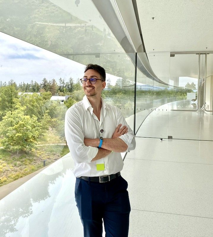 Antonio Braccolino smiling, arms crossed, in a glass corridor